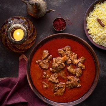 Overhead shot of Mutton Korma or Lamb Korma in wooden bowl with saffron rice on the side