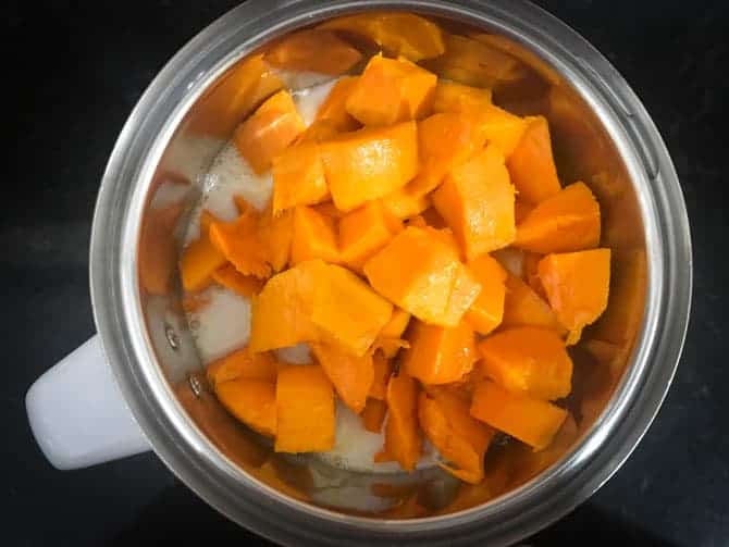 Fresh mango cubes added in a blender jar.