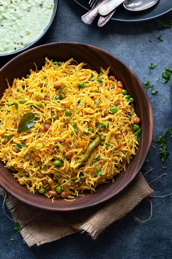 Overhead shot of semiya upma served in wooden bowl with coconut chutney on side.