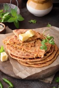 Close up shot of mooli ka paratha topped with butter, one paratha cut open to show the stuffing within.