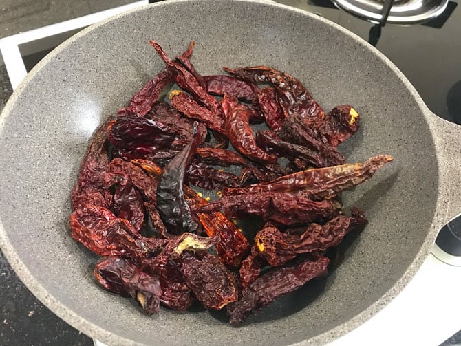Whole dried red chilies dry roasting in pan.