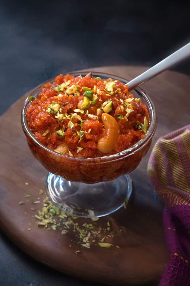 Close up shot of dry fruits garnished carrot halwa or gajar ka halwa sweet in a glass bowl.