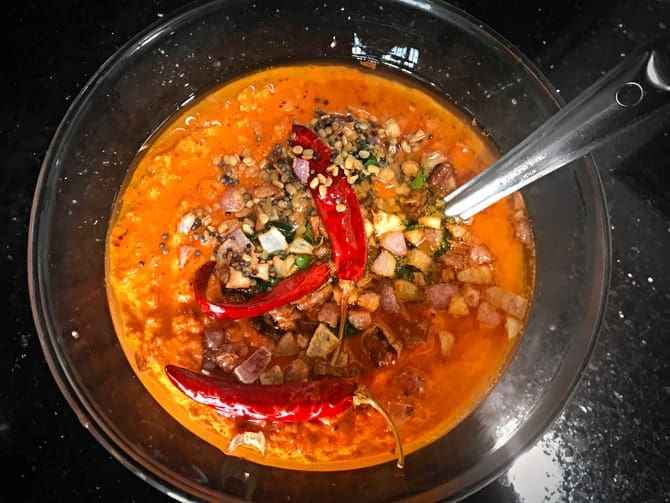 Tempering or tadka poured over the rede coconut chutney in bowl.