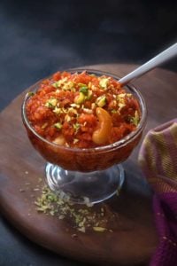 Close up shot of dry fruits garnished carrot halwa or gajar ka halwa sweet in a glass bowl.