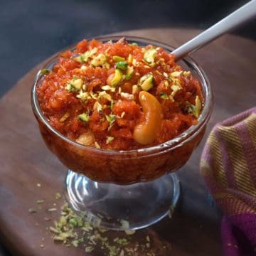Close up shot of dry fruits garnished carrot halwa or gajar ka halwa sweet in a glass bowl.