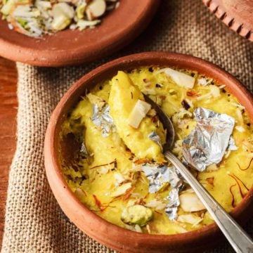 Close up shot of kesar phirni sweet in earthen pot with a spoon.