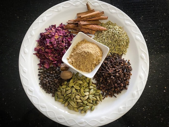 Chai masala ingredients on white plate.