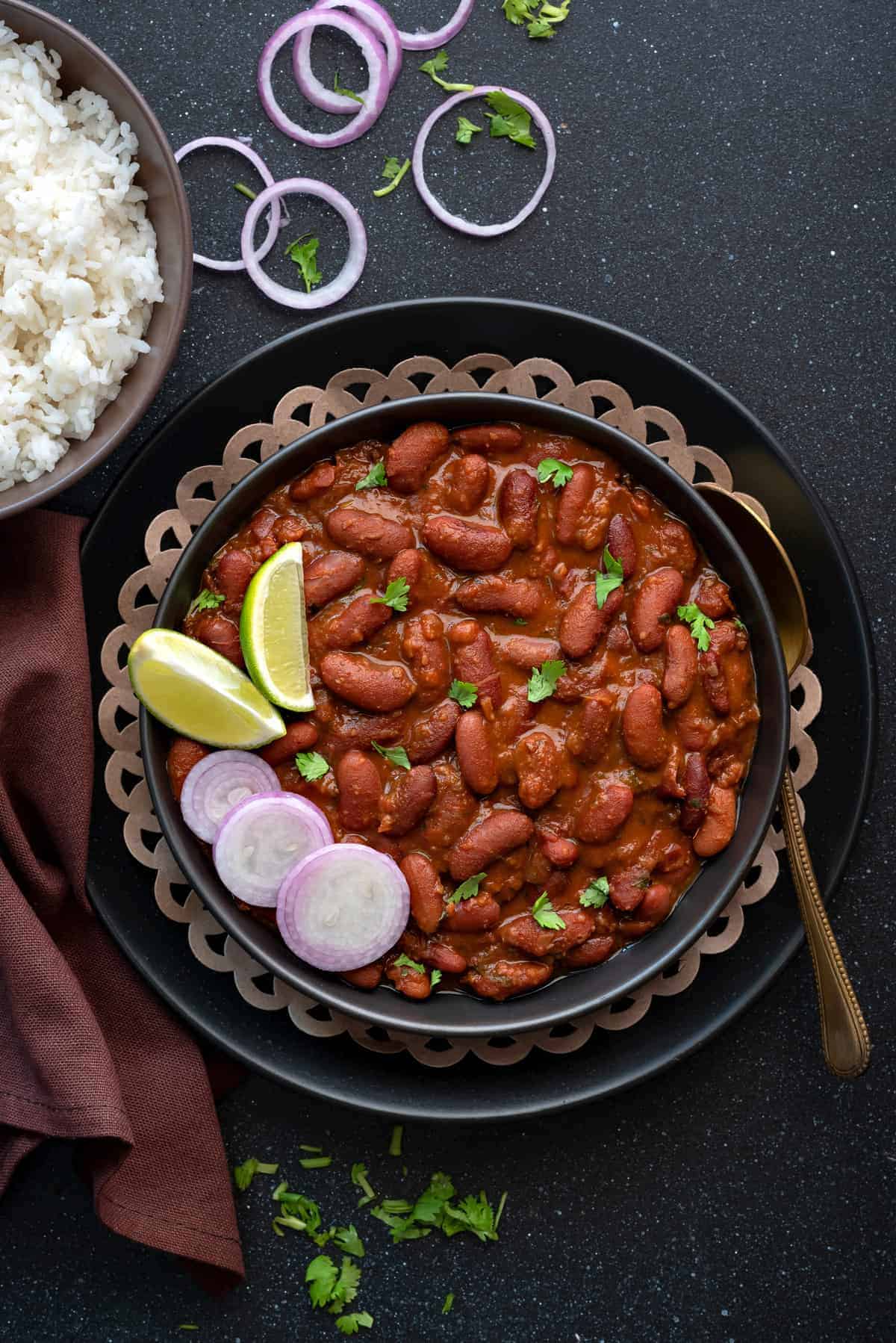 Punjabi Rajma masala served in black plate with a spoon into it.