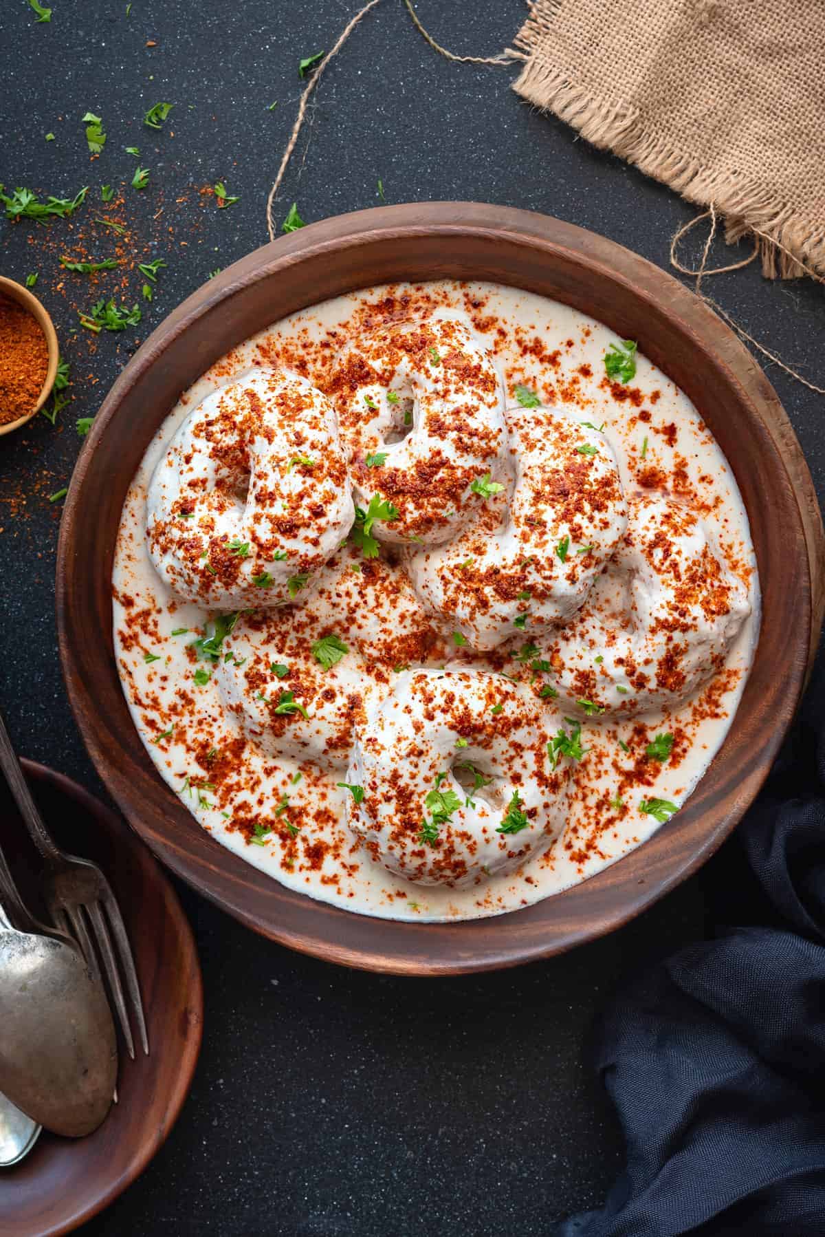 Close up shot of soft Dahi Vada served in wooden bowl.