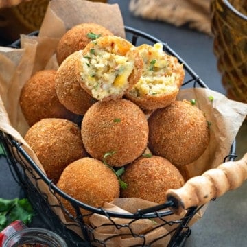 Corn cheese balls served in basket with one ball cut open showing the texture inside.