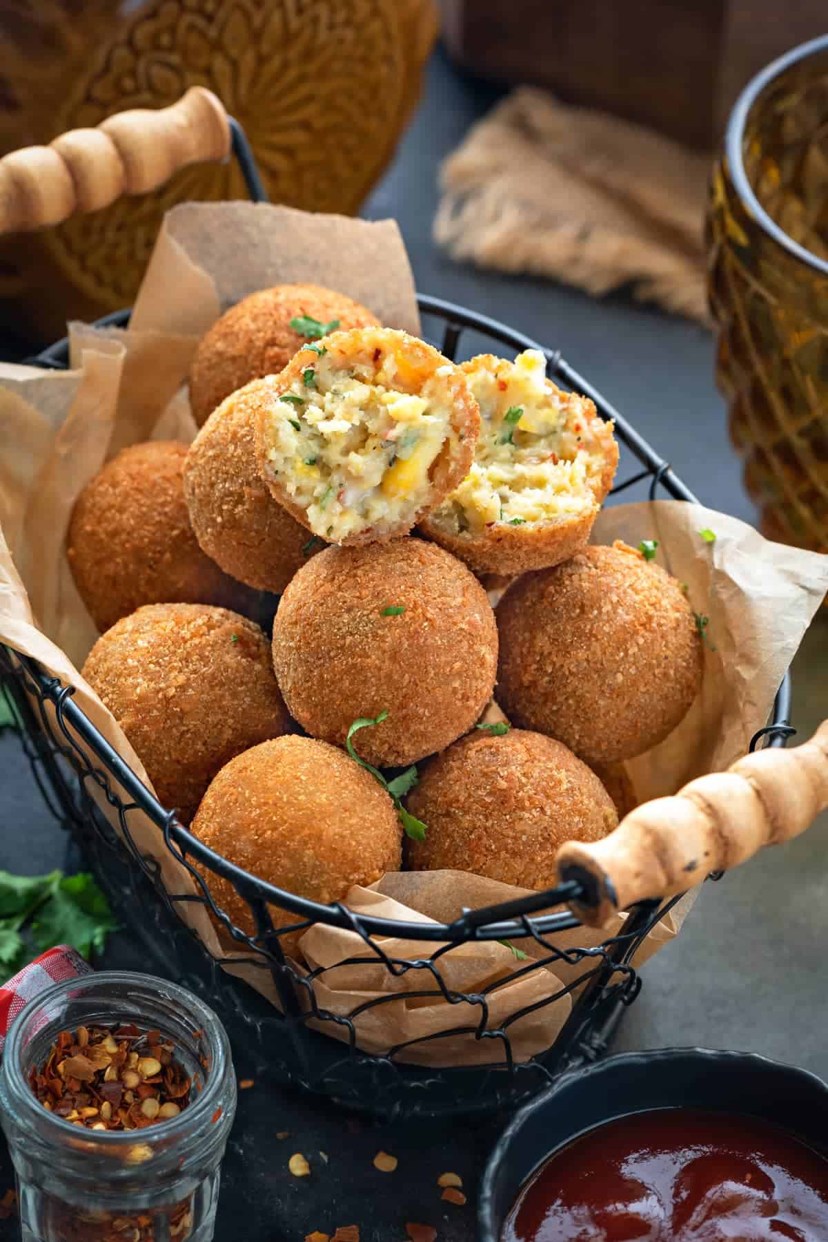 Corn cheese balls served in basket with one ball cut open showing the texture inside.