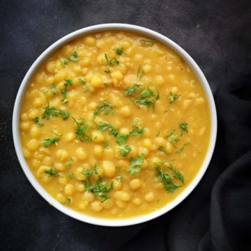 Delicious Ragda or white peas curry served in white bowl, black cotton linen at the side.