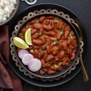 Punjabi Rajma masala curry served in black plate with a spoon into it.