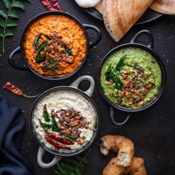 Red, white and green coconut chutney in 3 different black bowls.