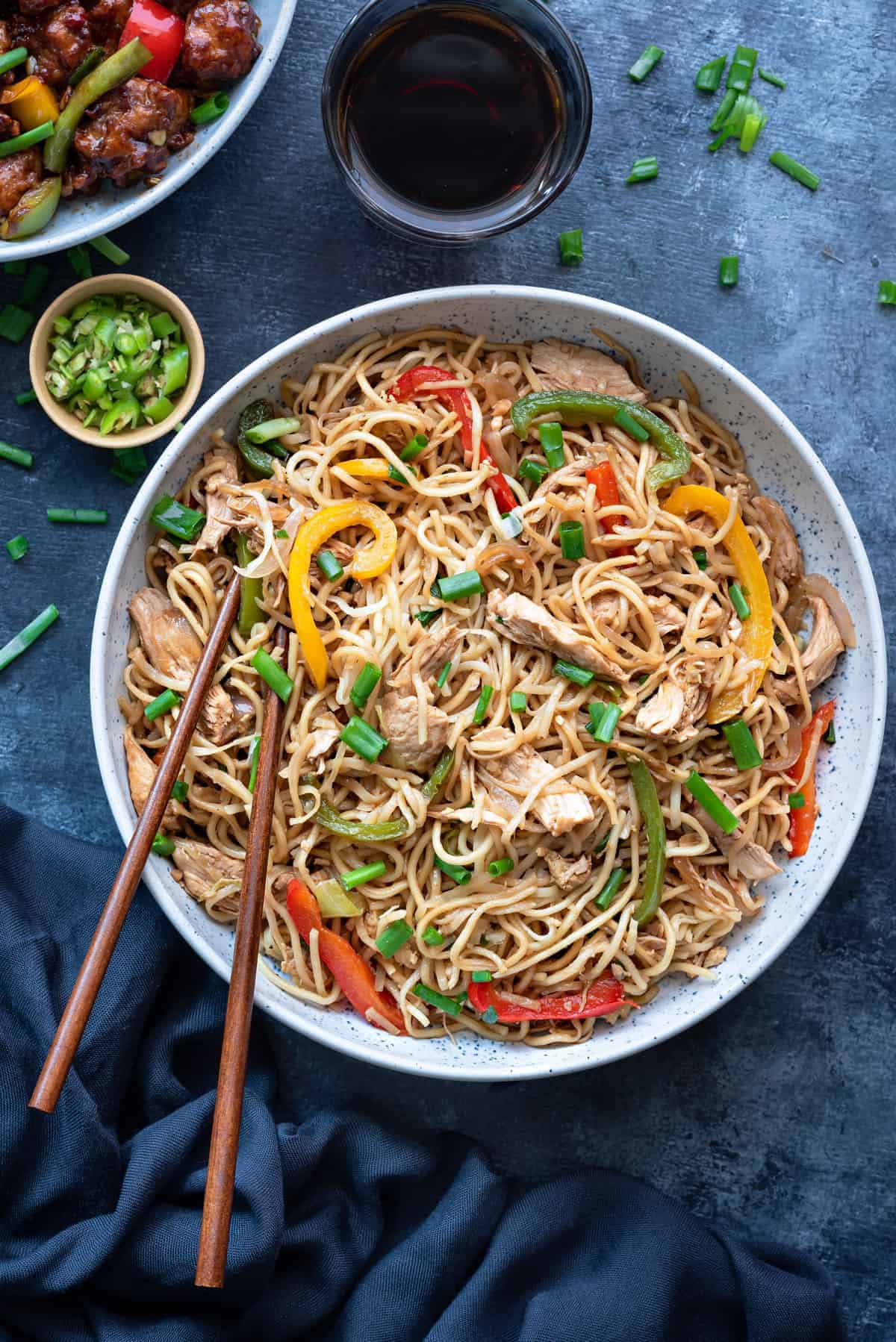 Chicken Hakka Noodles in blue bowl with pair of chopsticks into it.