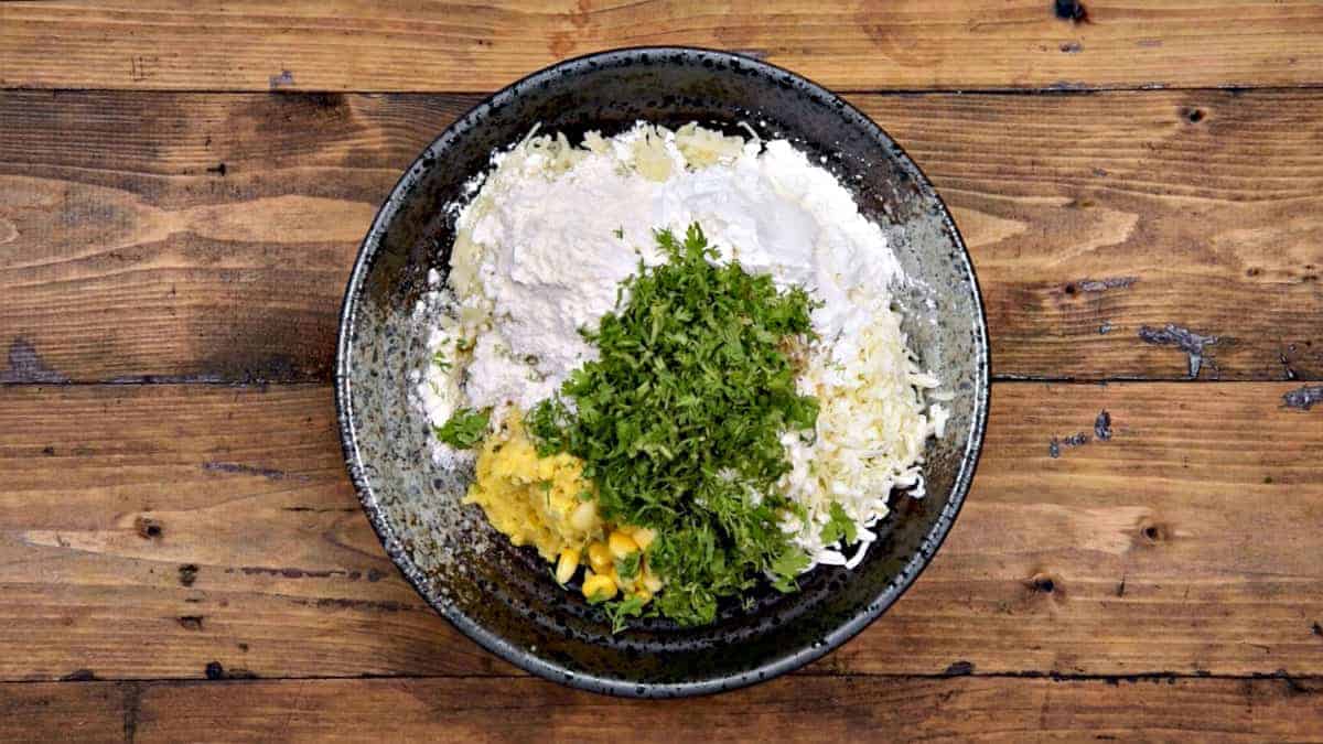 Cornflour, plain flour and chopped coriander leaves added in bowl.