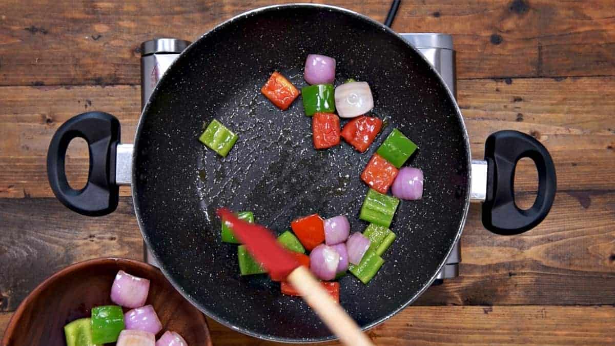 Transferring the roasted onion capsicum and tomatoes on to a plate.