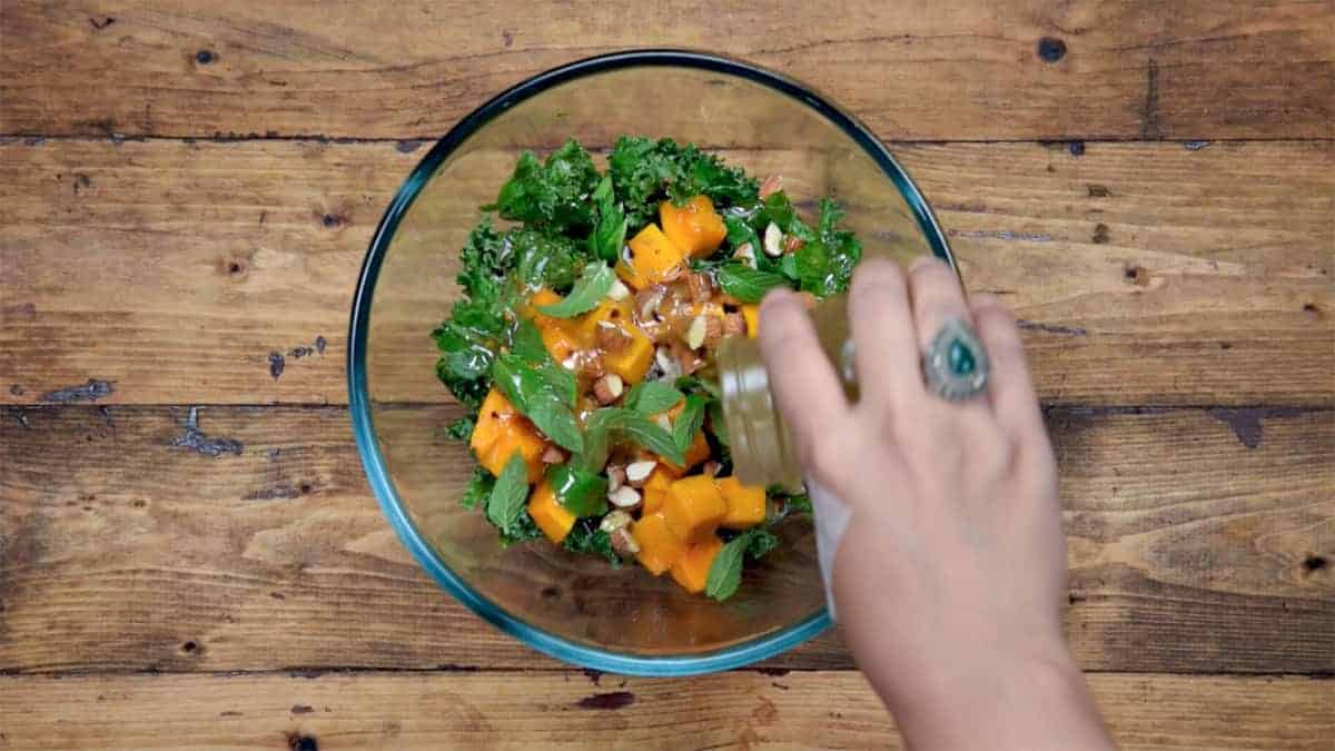 Adding Lemon Dressing over the Mango Kale mixture in bowl.