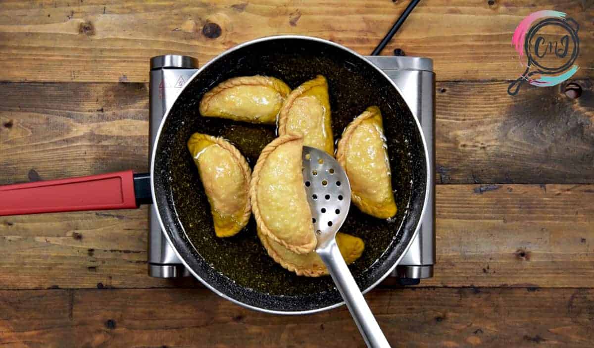 Golden brown fried Gujiya in pan.