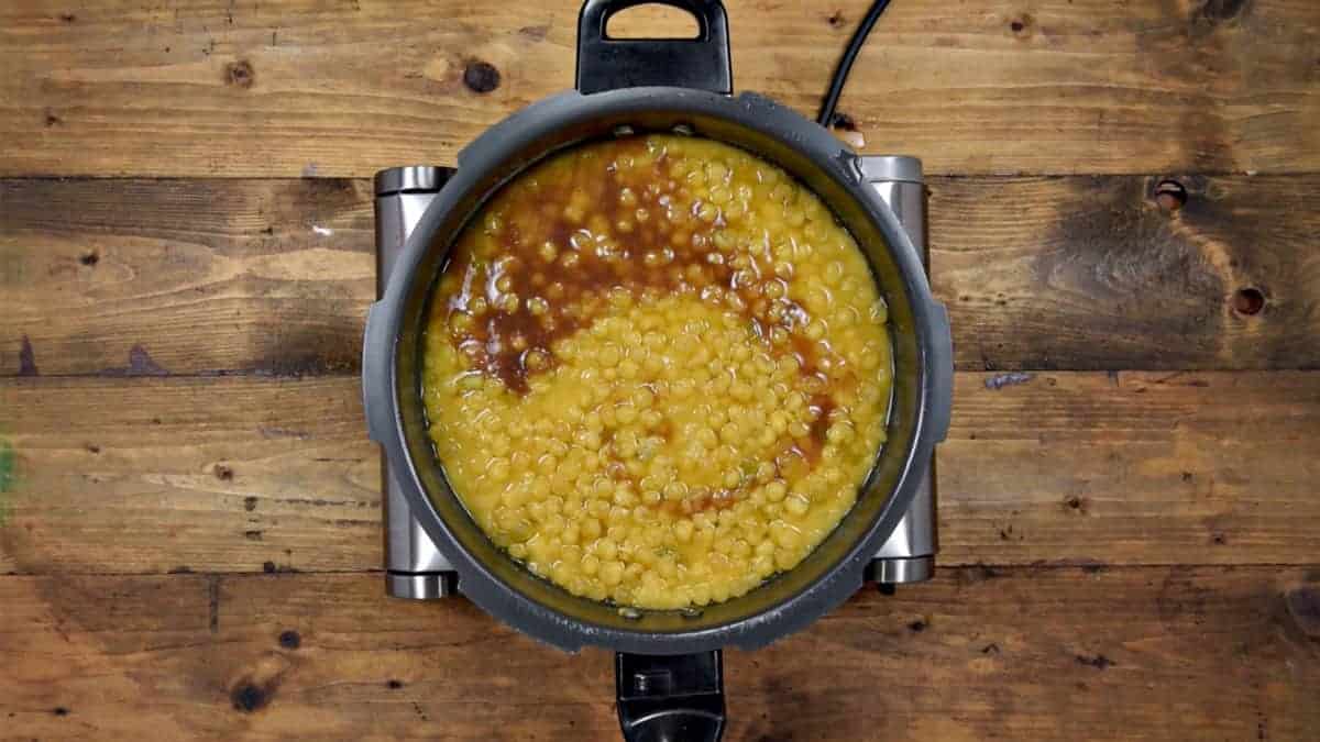 Tamarind pulp added to cooked ragda in pressure cooker.