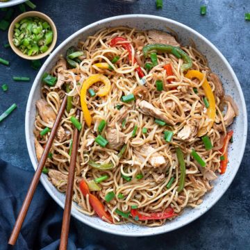 Chicken Hakka Noodles in blue bowl with pair of chopsticks into it.