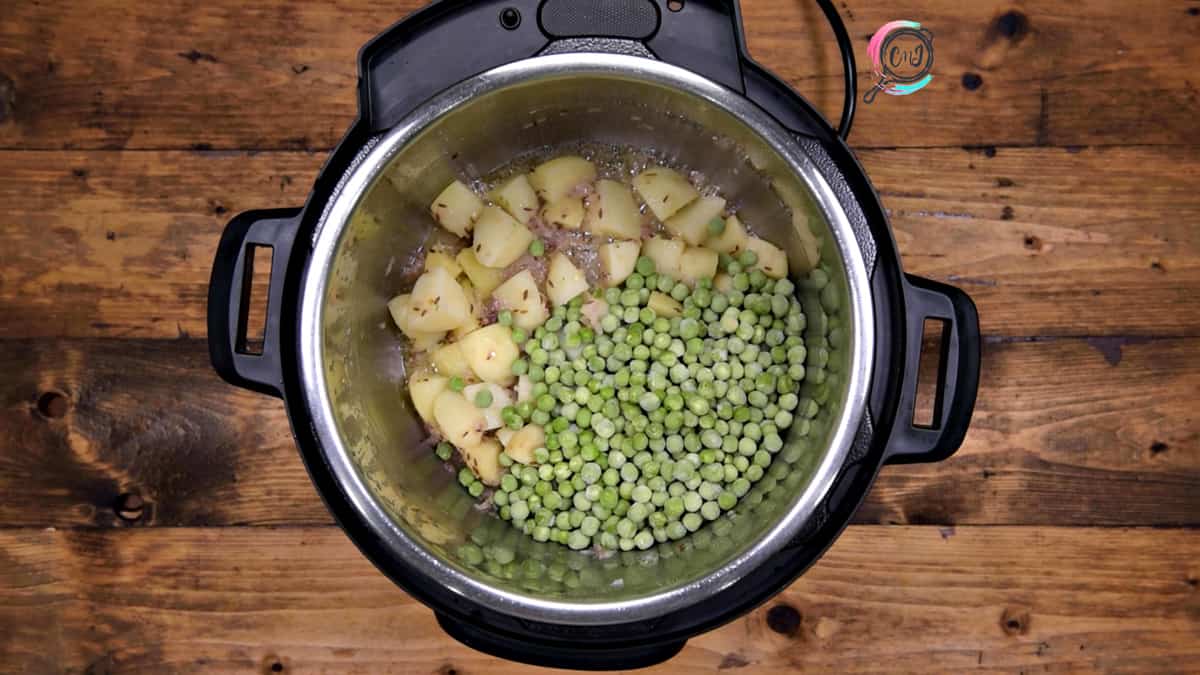 Green peas added to the sautéed potatoes in pot.