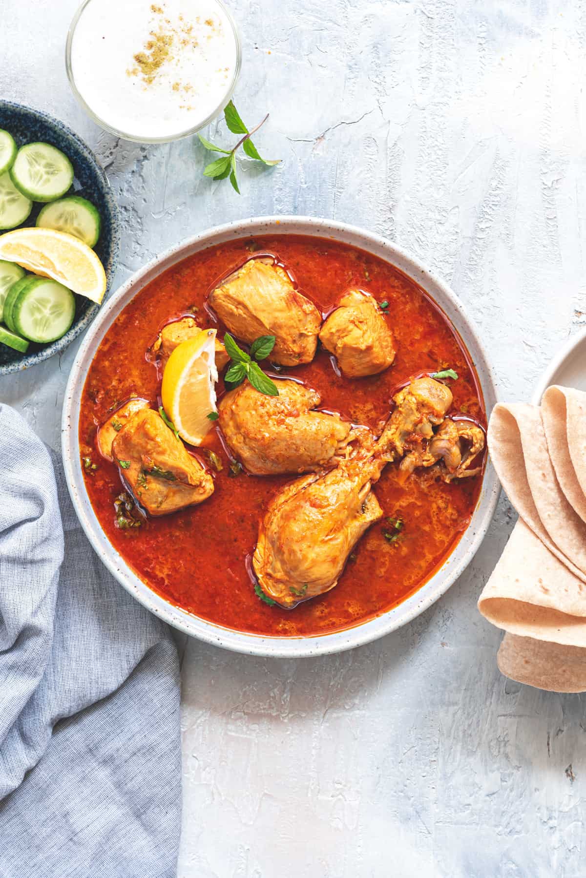 Chicken Curry served in white bowl with bread and salad on side.