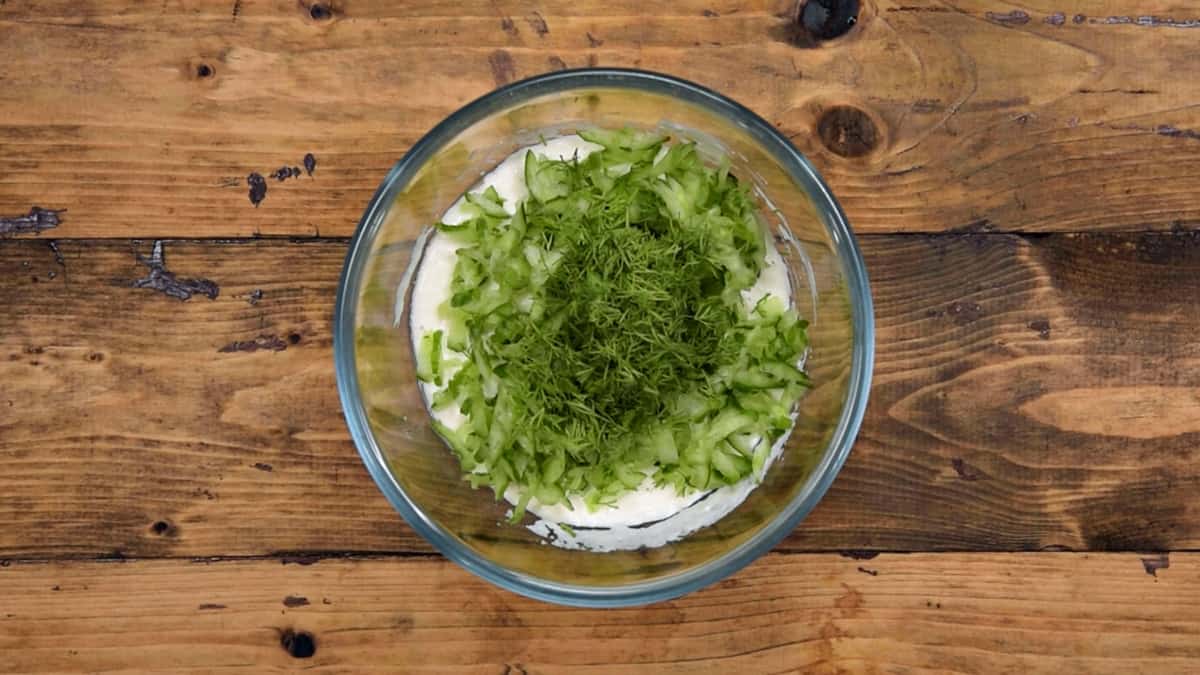Squeezed cucumber and chopped dill leaves added in prepared yogurt mixture to make Tzatziki sauce.