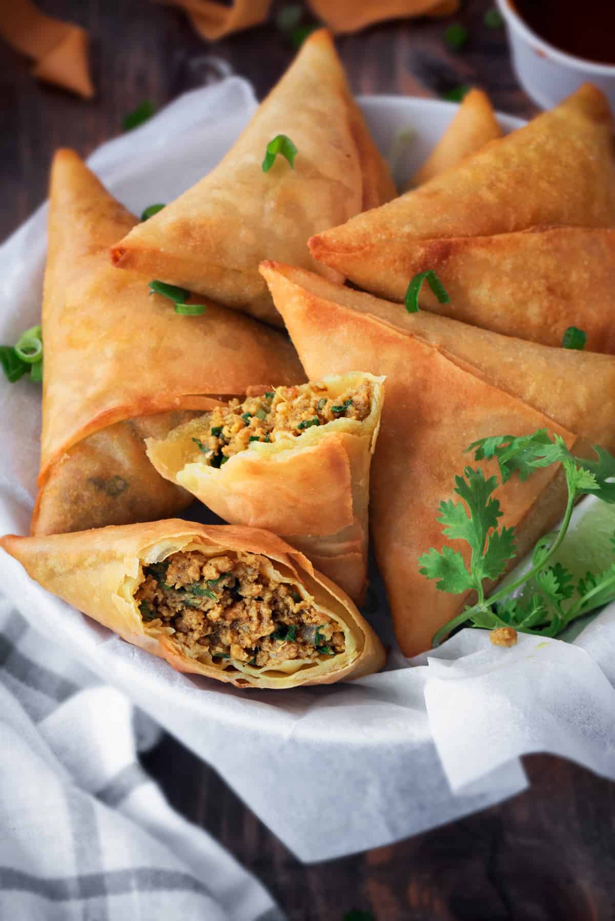 close up shot of plated keema samosa with one broken open to show the meat filling