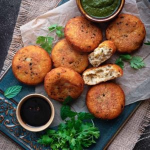 Crispy aloo tikki with one patty open served with chutney on blue ceramic tray.