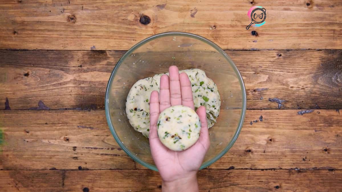 A palm showing round shaped potato tikki or patty.