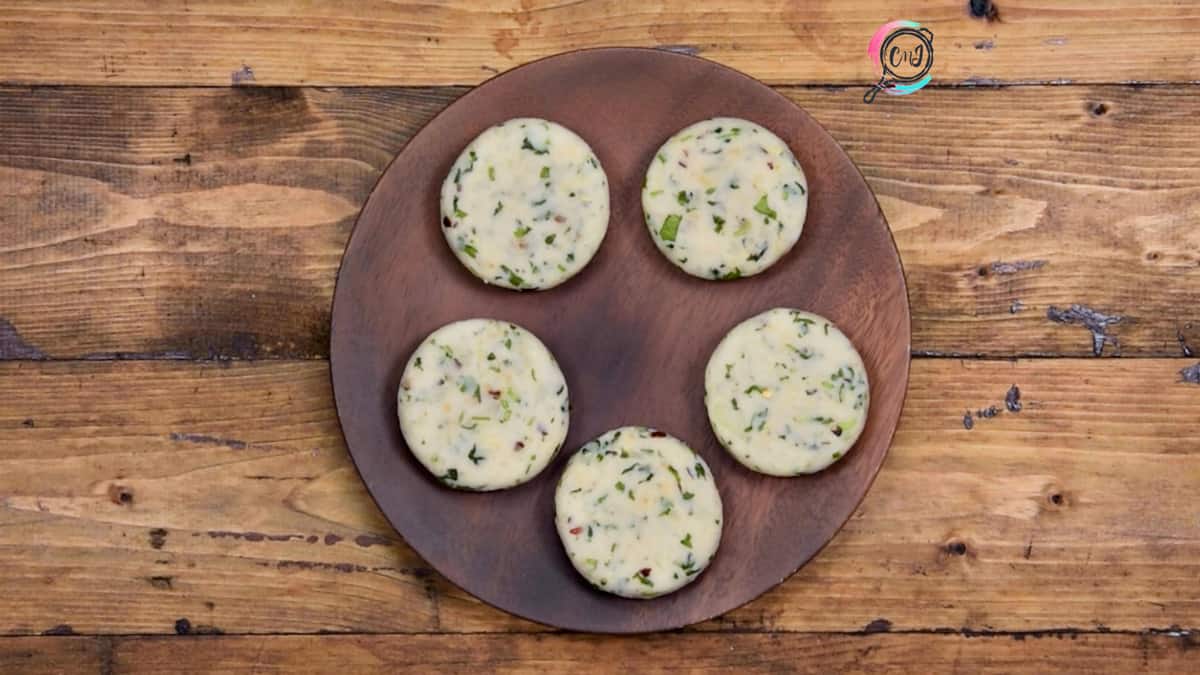 5 shaped aloo tikkis or patties placed on a wooden plate.