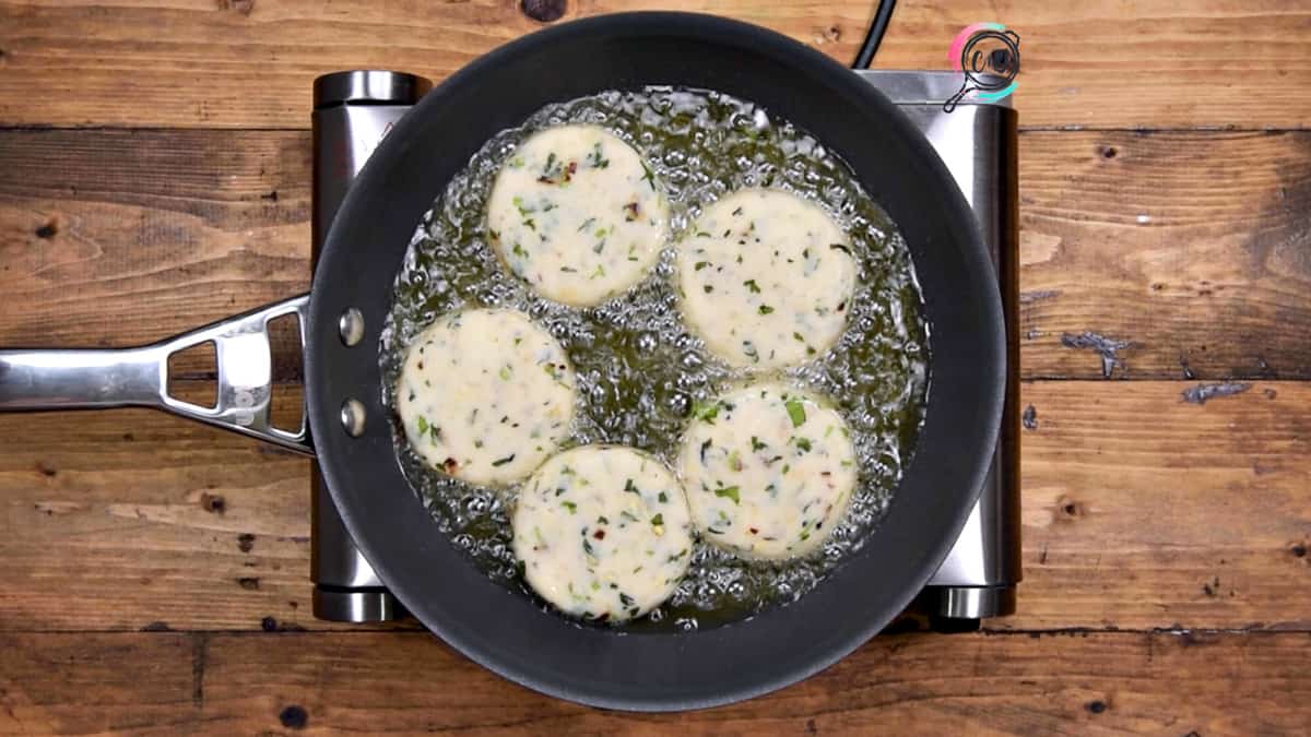 5 patties shallow frying in oil in pan.