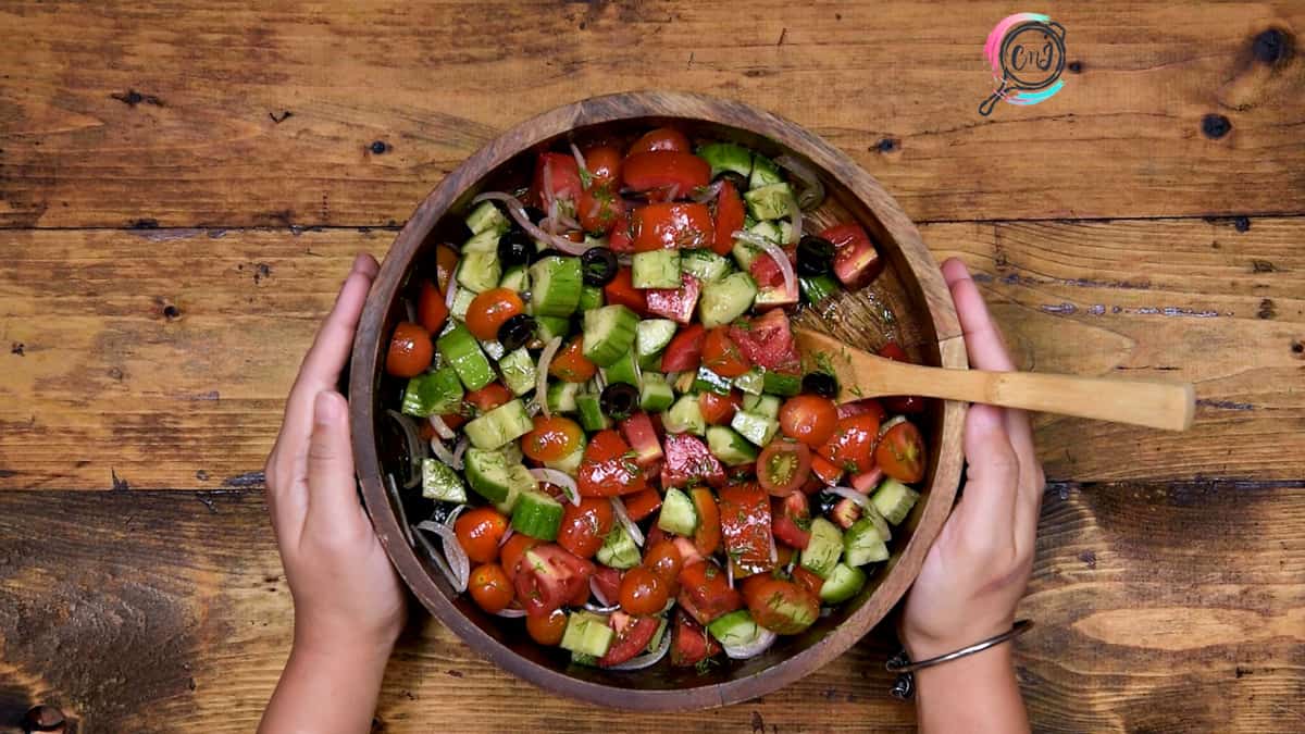 Tossed cucumber tomato onion salad in wooden bowl ready to serve.