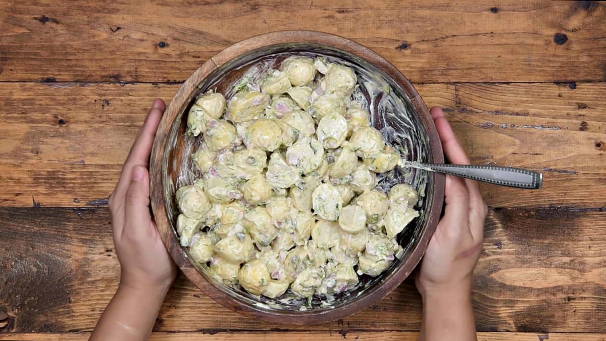 Tossed lemon dill potato salad in wooden bowl.