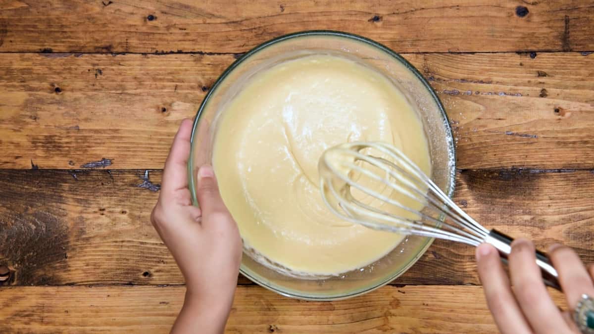 Whisking the mixture using a wire whisk to make pancake batter.