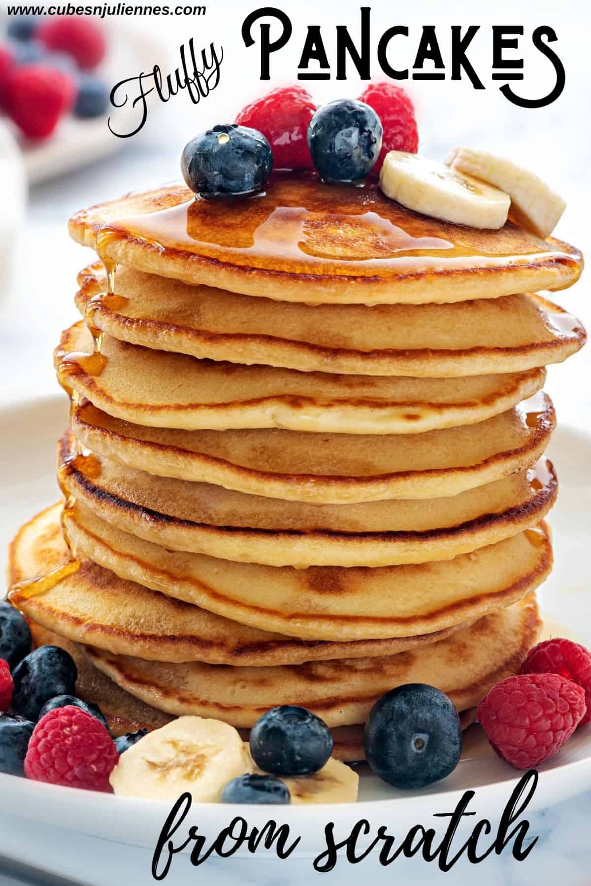 Close up shot of stacked pancakes topped with maple syrup, berries and banana slices.