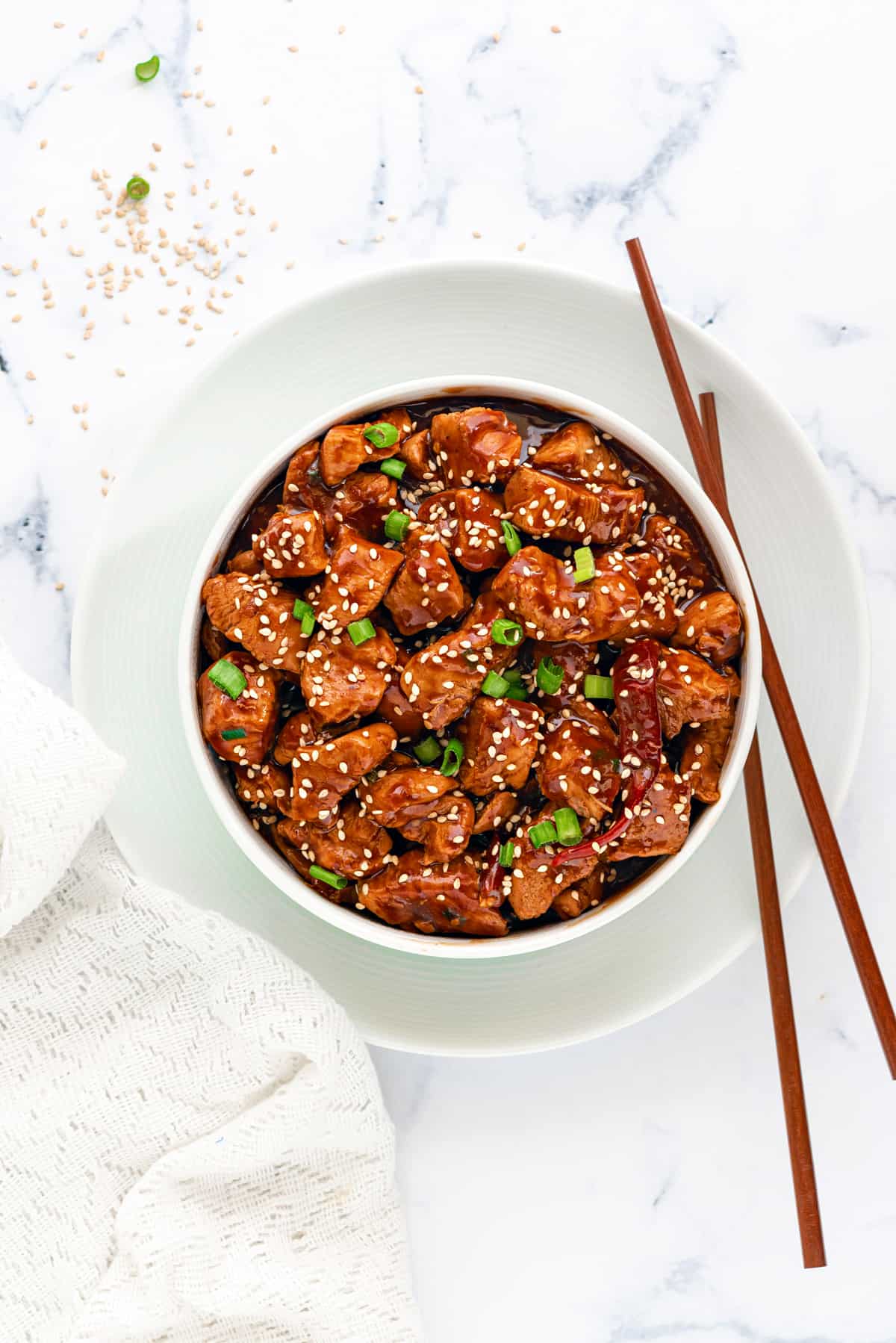 Instant Pot General Tso Chicken gravy in white bowl with a pair of chopsticks on side.