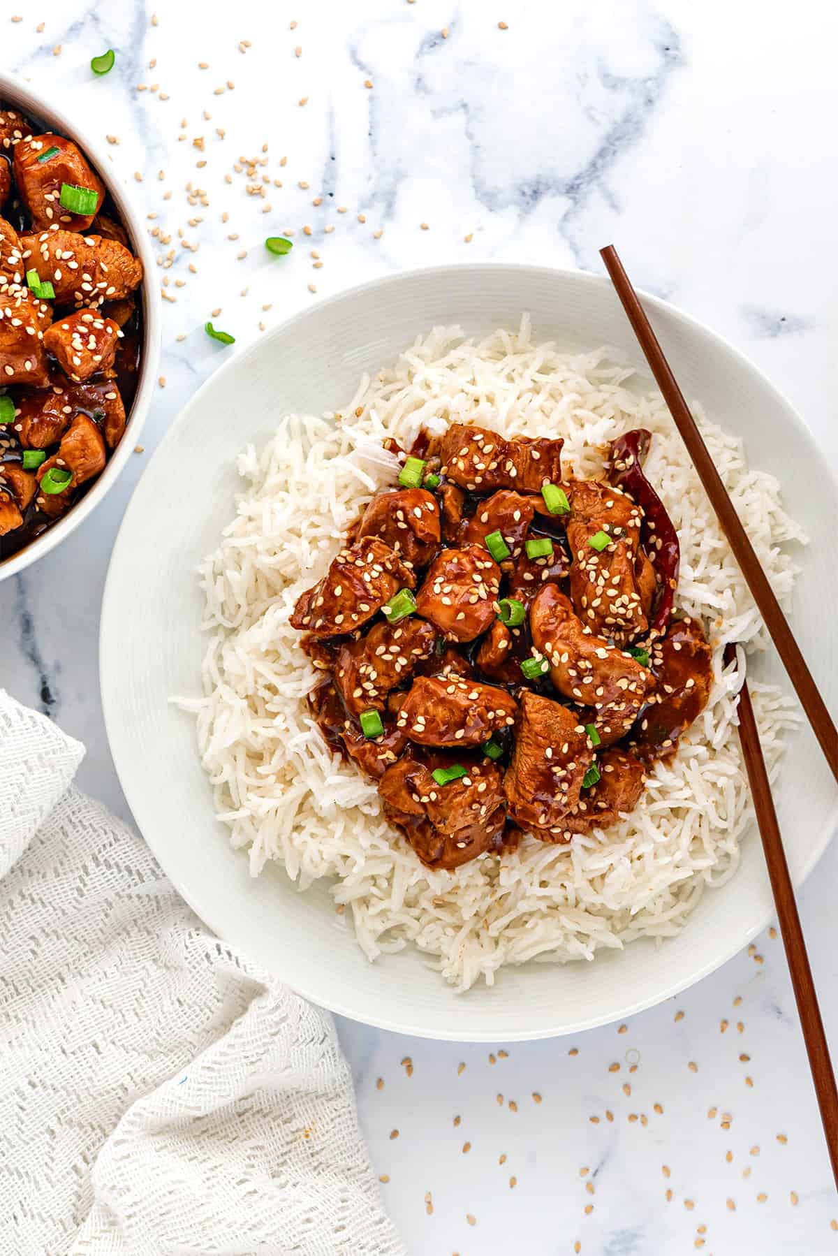 White steamed rice topped with Instant Pot General Tso's chicken gravy served in white plate.