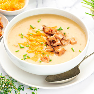 Creamy Instant Pot Potato Soup in white bowl with spoon on side.