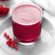 Homemade Pomegranate juice served in glass, few arils spread around.