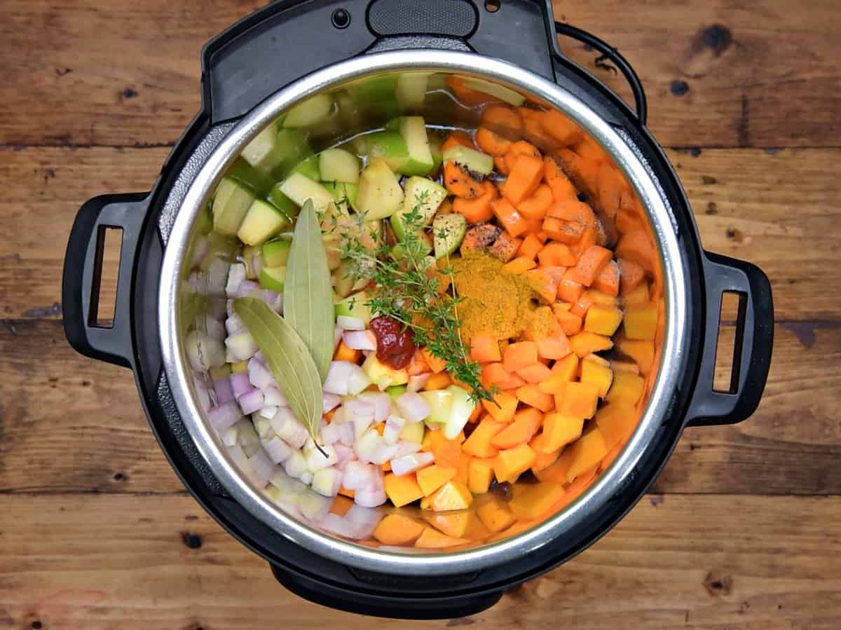 Butternut squash, apple, carrot, onion, spices, herbs and stock added in Instant Pot.