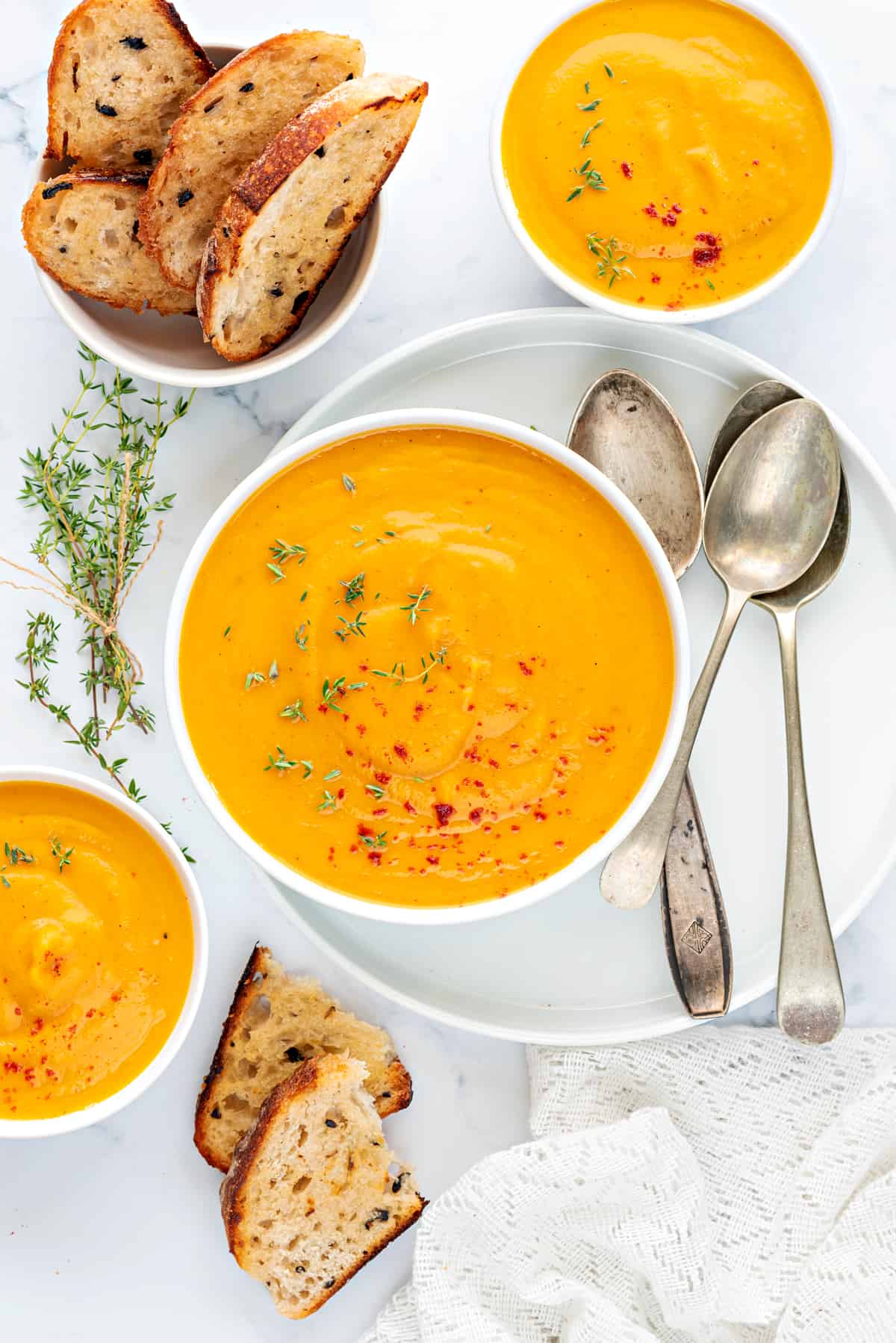 Curried butternut squash soup served in 3 white bowl with toasted bread on the side.