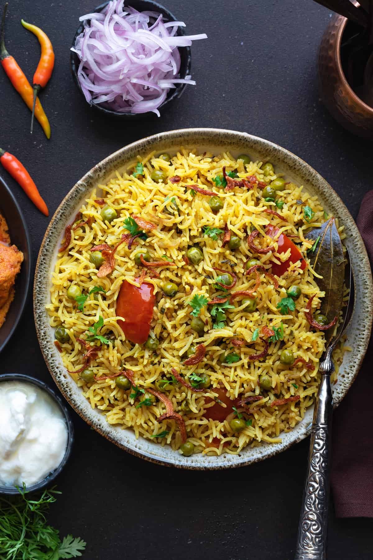 Close up shot of spicy matar pulao in bowl with spoon in it.