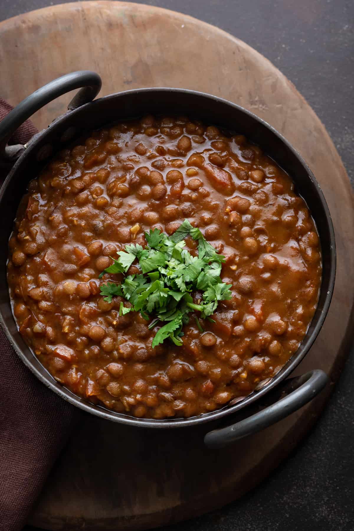 Whole Masoor Dal Lentil Curry garnished with cilantro in Indian wok kadai.