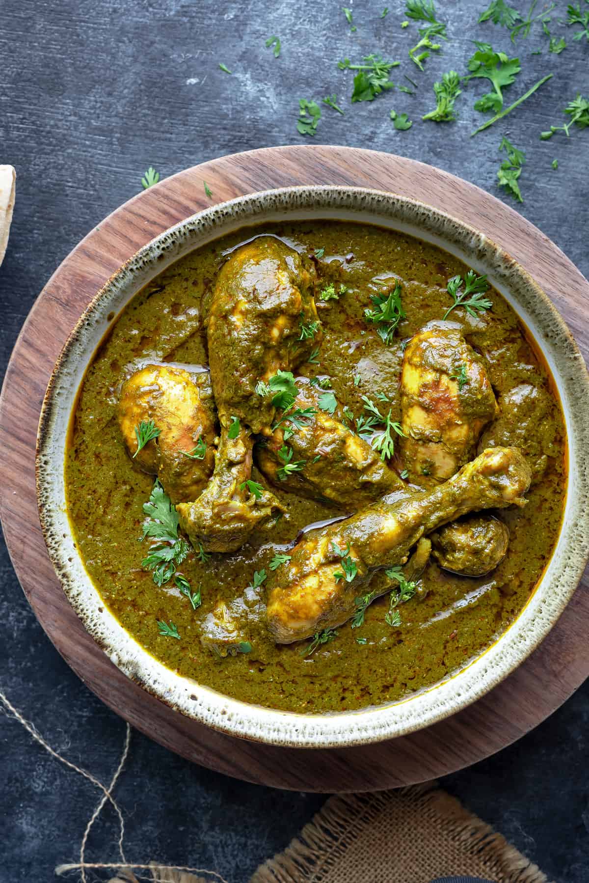 close up of chicken saag curry served in a grey ceramic bowl.