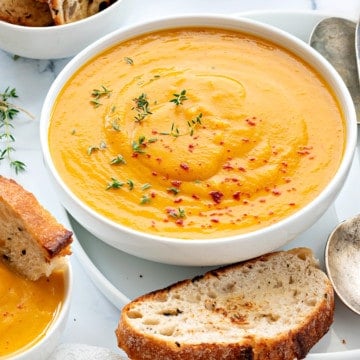 Side angle shot of curried Instant pot butternut squash soup in white bowl with toasted bread.