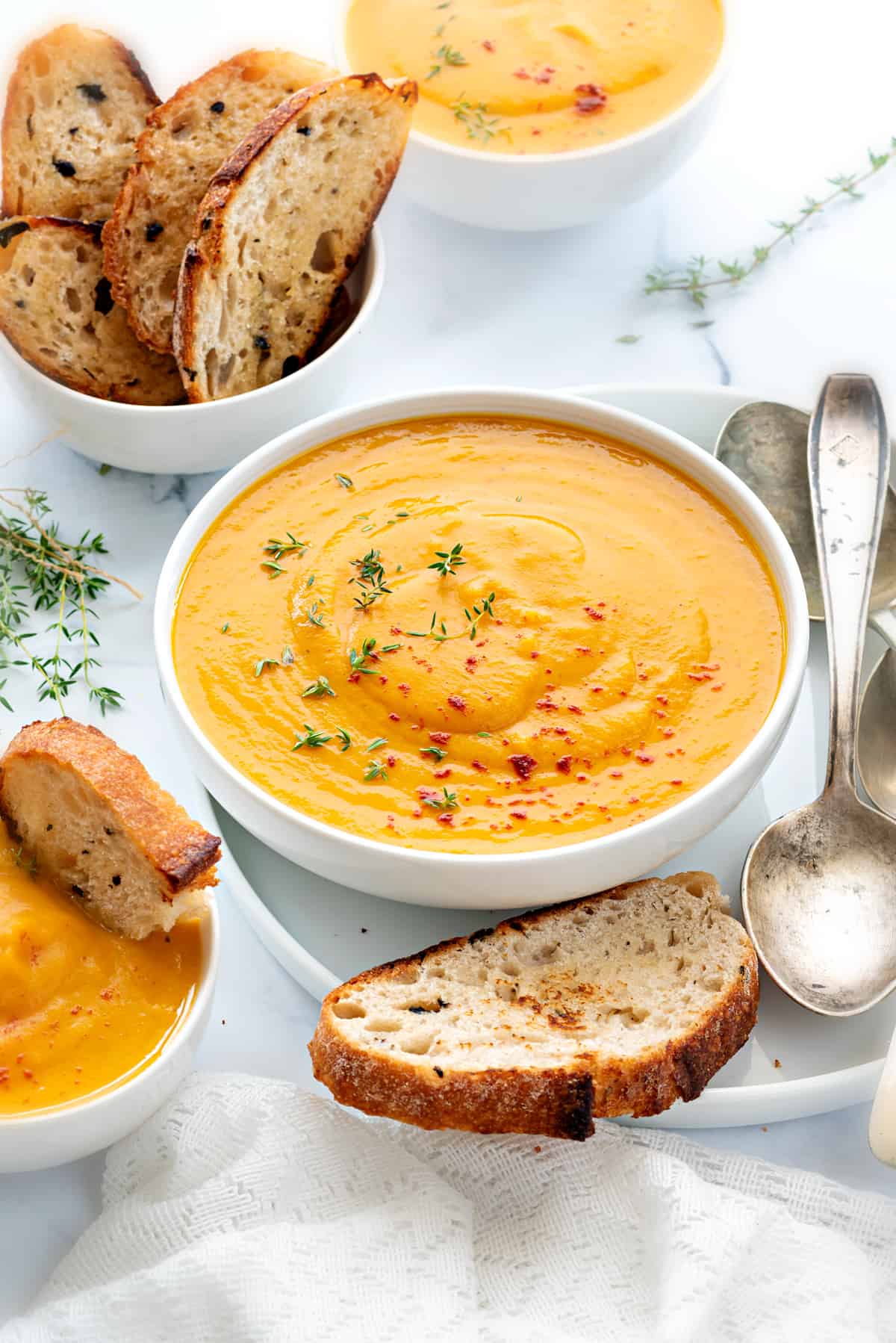 Curried butternut squash soup in white bowl with bread on side.