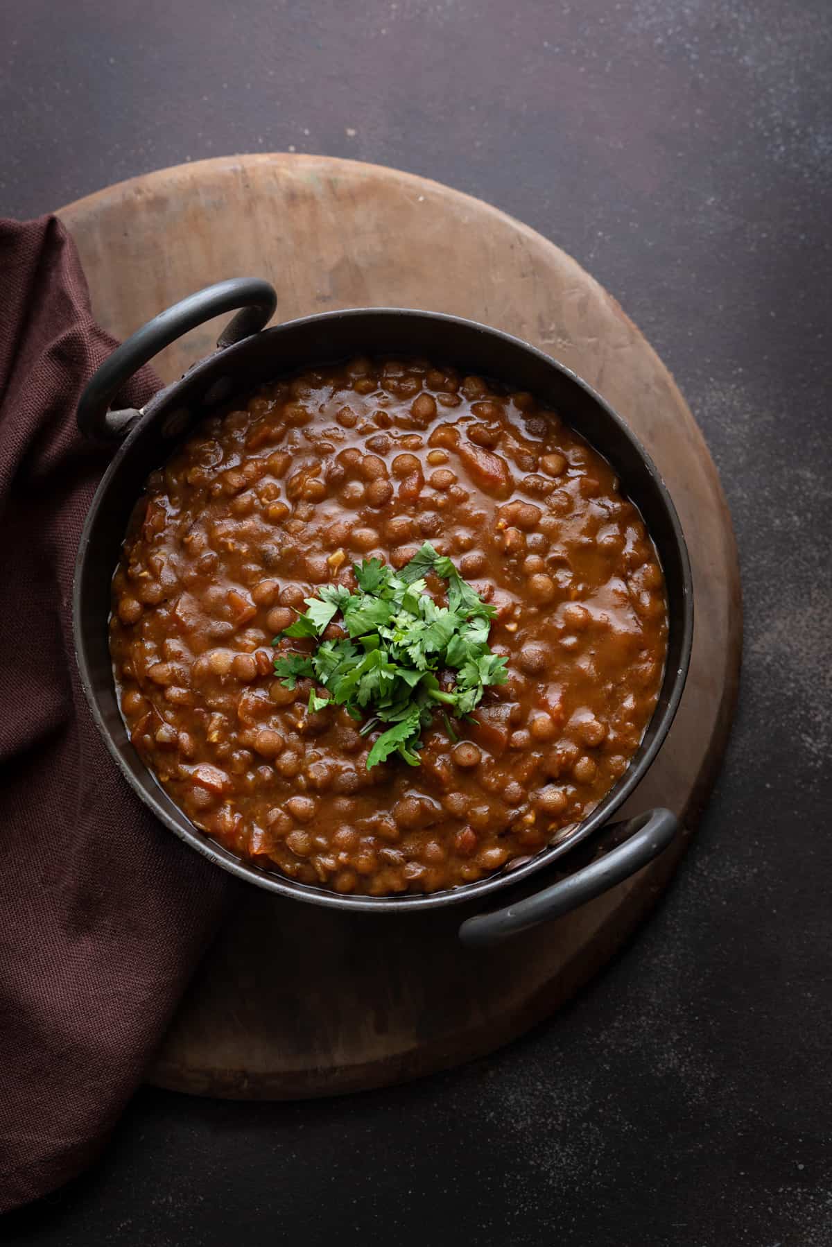 Whole Masoor Dal garnished with cilantro and served in Indian kadai.