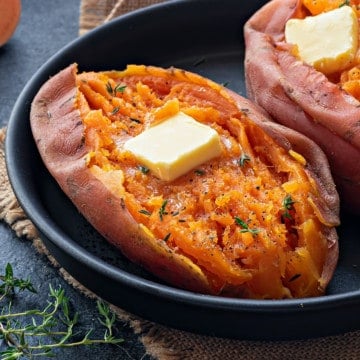 Close up shot of mashed Instant Pot Sweet Potatoes with butter cube on black plate.